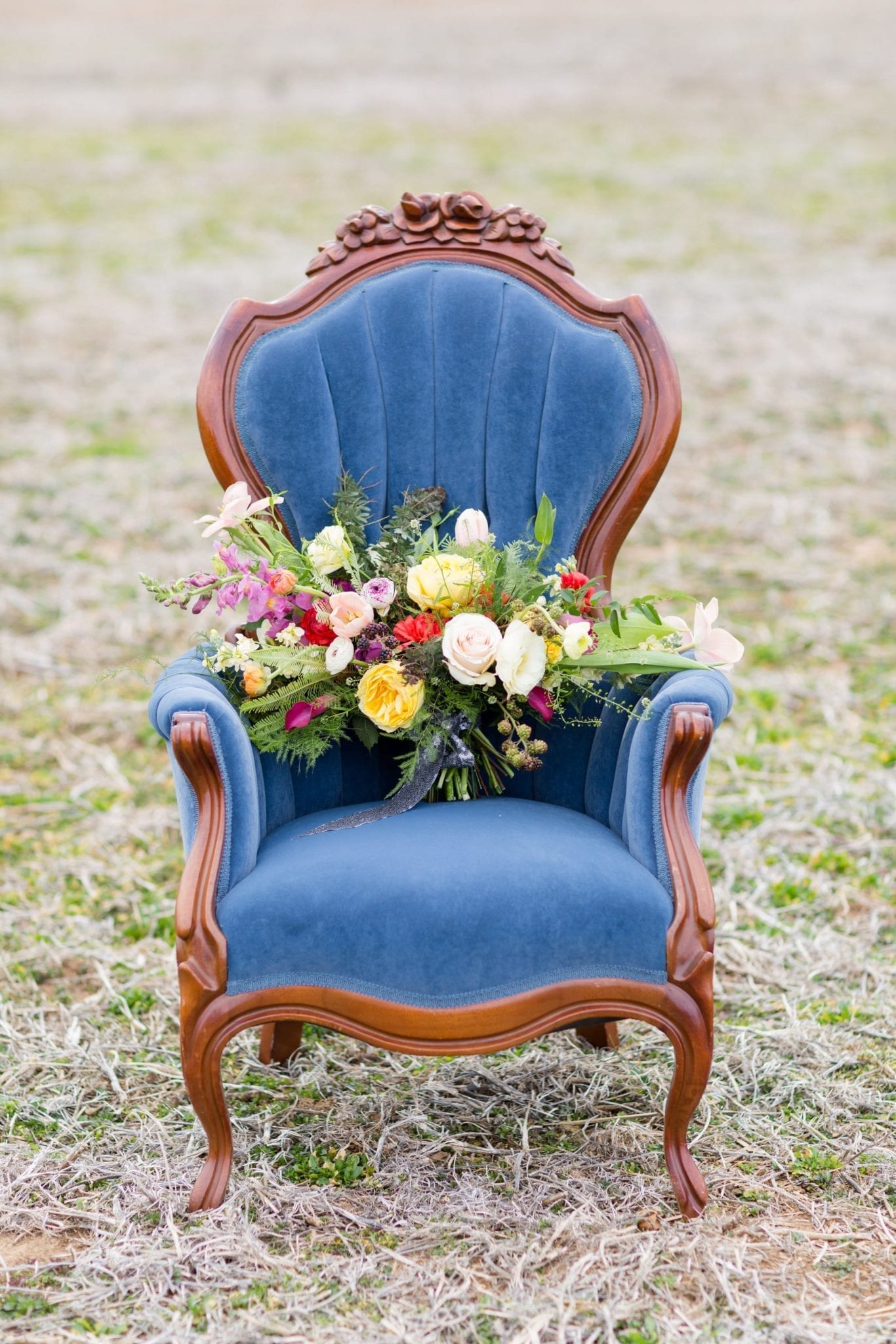 Victorian chair with beautiful tufted cobalt blue velvet upholstery and carved wood with flowers. Photo by Lisa Mims Photography.